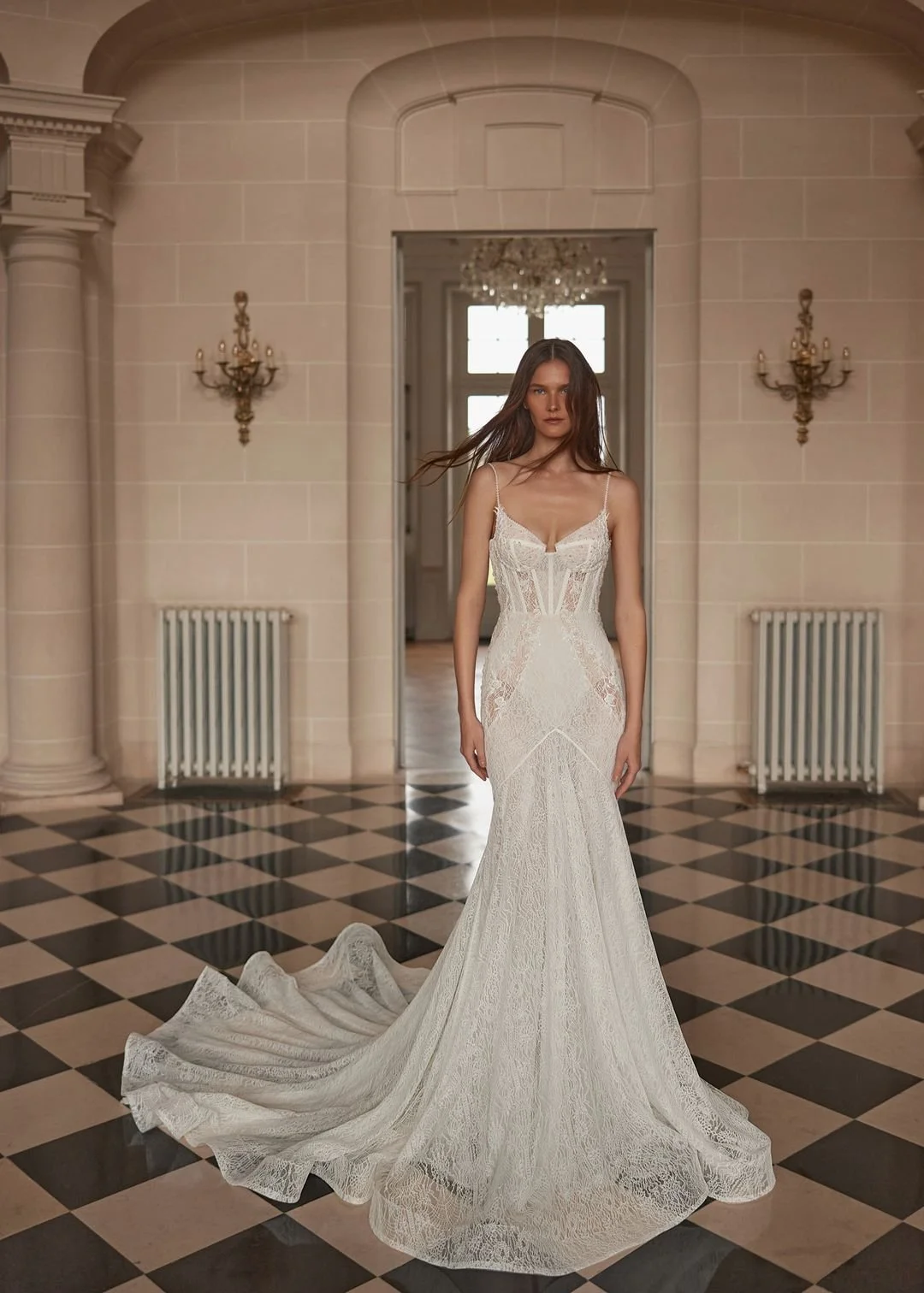A bride in a white lace wedding dress standing in an elegant historic hall